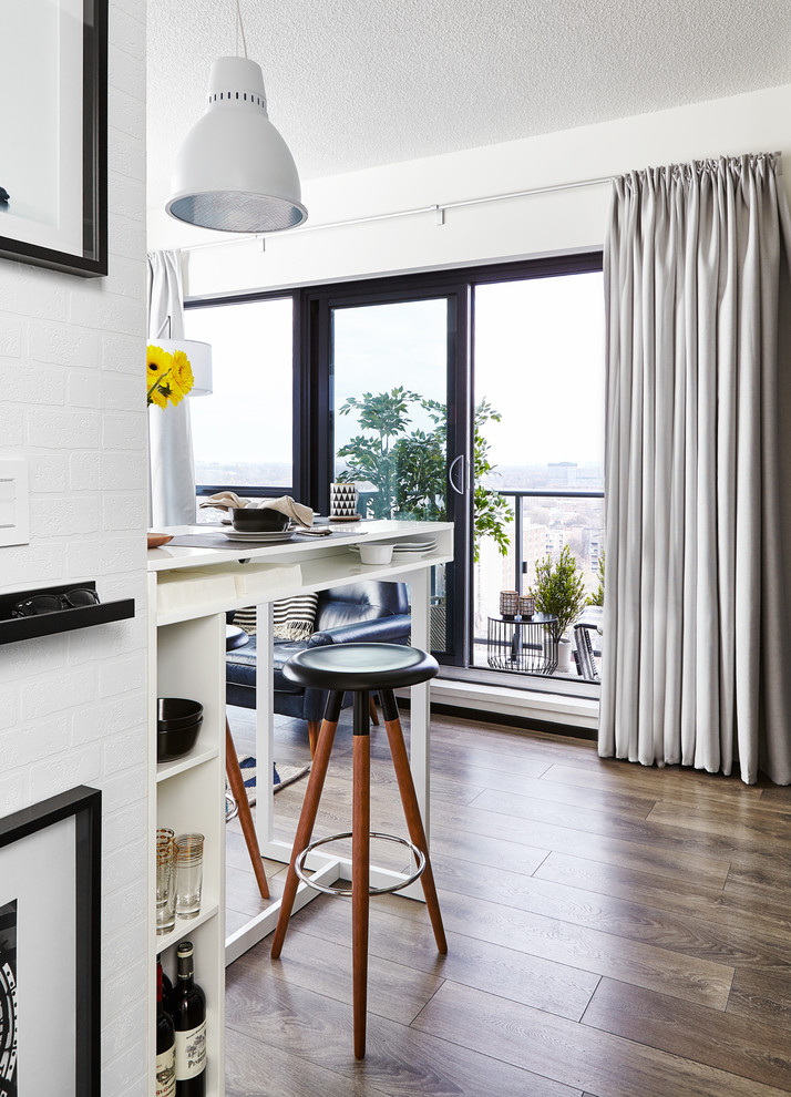 Immagine di un piccolo soggiorno design aperto con pavimento in laminato, TV autoportante, pavimento marrone e pareti bianche