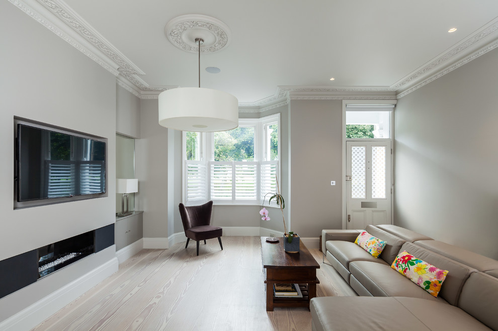 Exempel på ett modernt separat vardagsrum, med ett finrum, grå väggar, ljust trägolv, en bred öppen spis och en väggmonterad TV