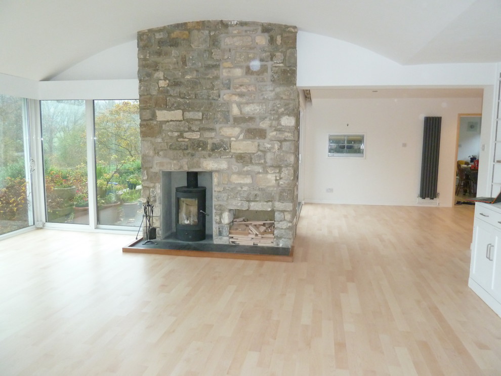 Geräumiges, Offenes Modernes Wohnzimmer mit hellem Holzboden, Kaminofen und Kaminumrandung aus Stein in Sonstige