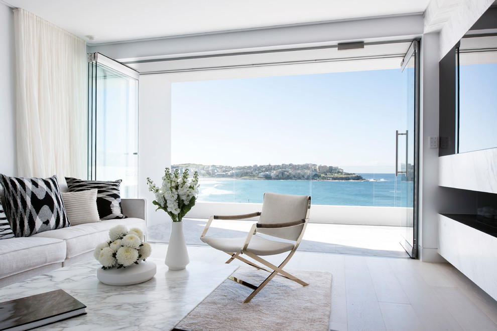 Offenes Modernes Wohnzimmer mit weißer Wandfarbe, hellem Holzboden, Gaskamin, Kaminumrandung aus Stein, TV-Wand und beigem Boden in Sydney