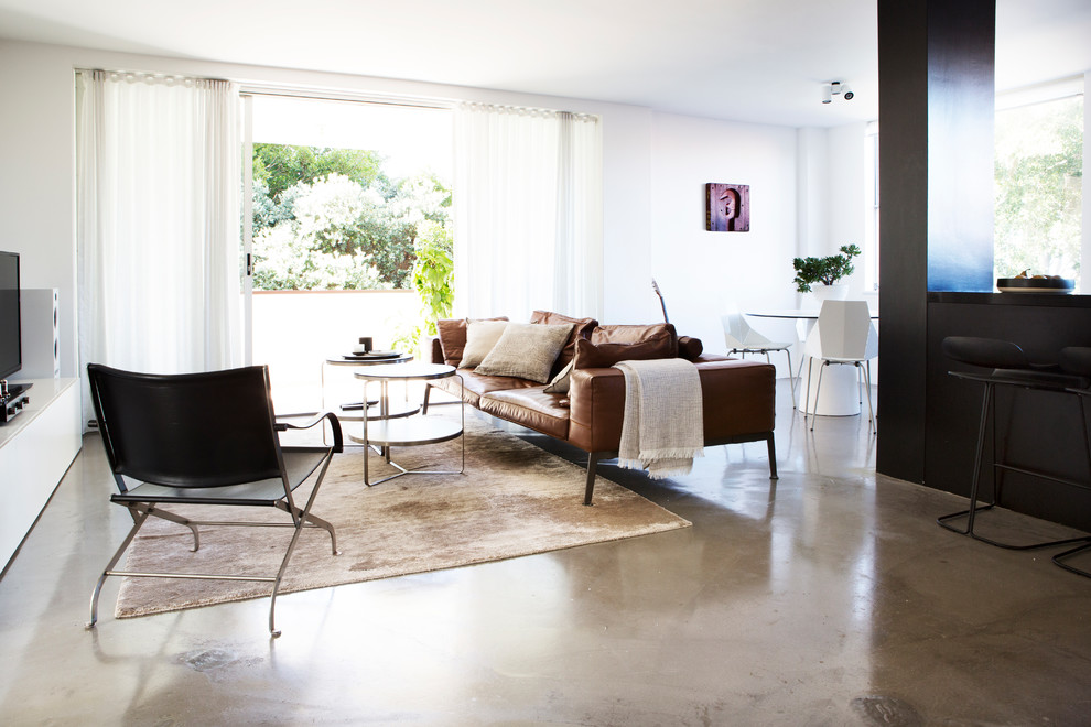 Imagen de salón abierto contemporáneo con paredes blancas, suelo de cemento y suelo gris