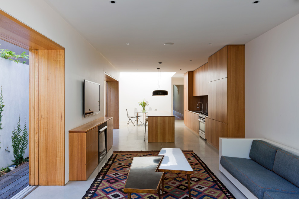 Источник вдохновения для домашнего уюта: открытая гостиная комната среднего размера в современном стиле с белыми стенами, бетонным полом, стандартным камином, фасадом камина из дерева и телевизором на стене