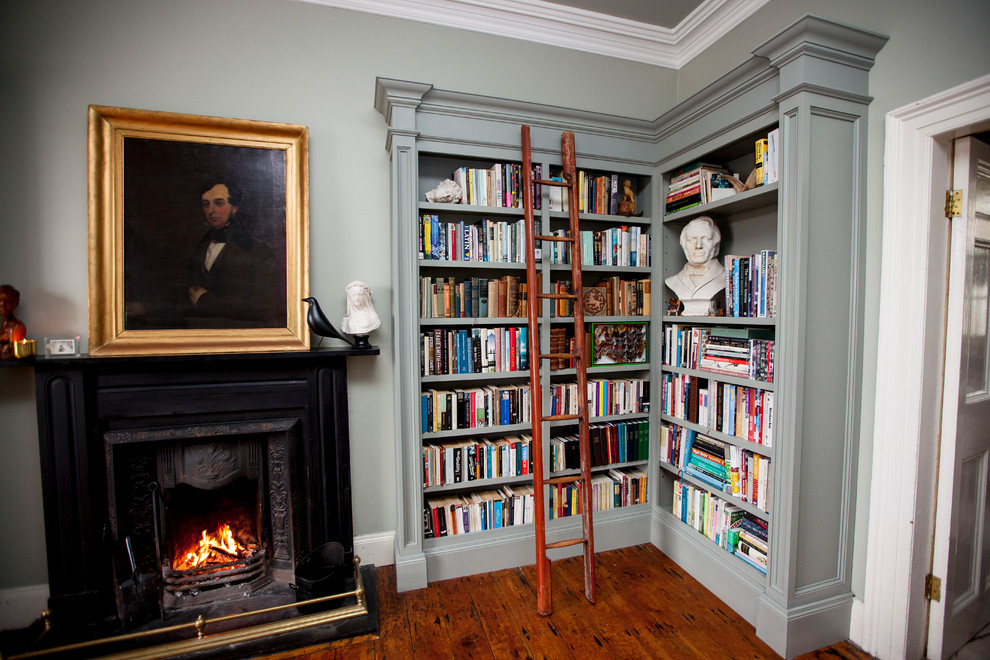 Idée de décoration pour un salon victorien de taille moyenne et fermé avec une bibliothèque ou un coin lecture, un mur gris, parquet foncé, une cheminée standard et un manteau de cheminée en bois.