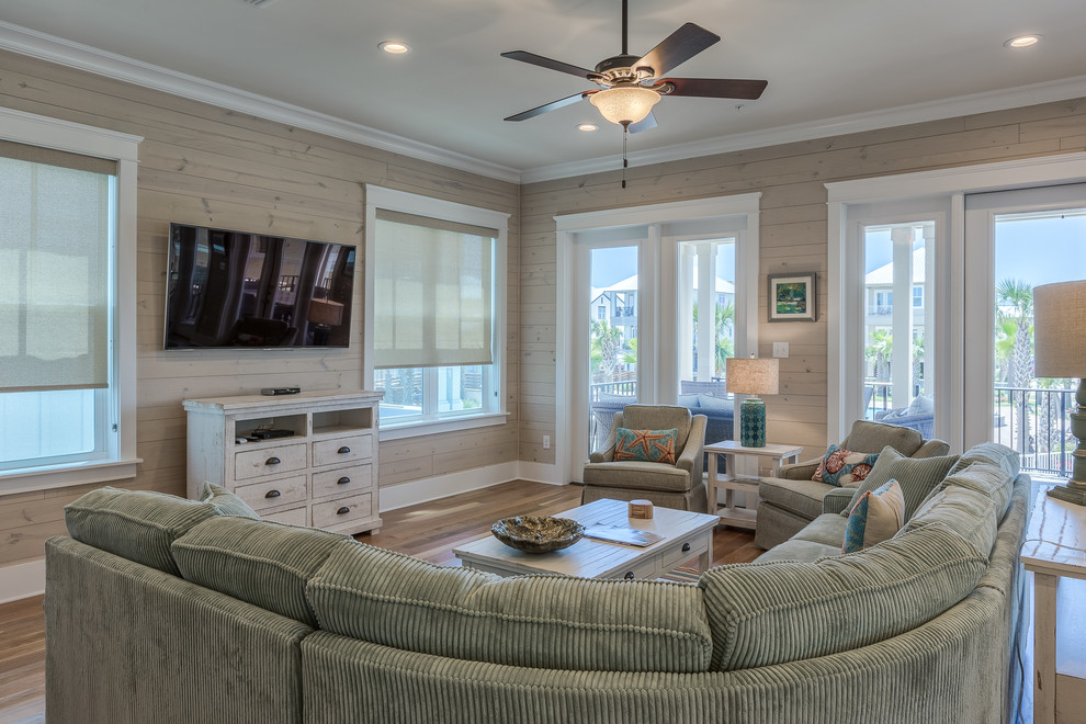 Example of a large beach style open concept medium tone wood floor living room design in Miami with beige walls and a wall-mounted tv