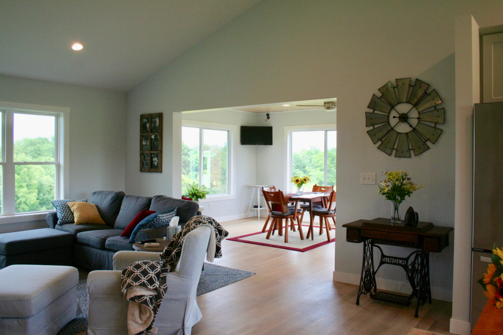 Imagen de salón abierto campestre de tamaño medio con paredes blancas, suelo de madera en tonos medios, estufa de leña y suelo marrón