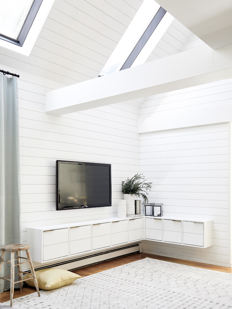 Cette image montre un grand salon marin ouvert avec un mur blanc, parquet clair, un téléviseur fixé au mur et un sol marron.