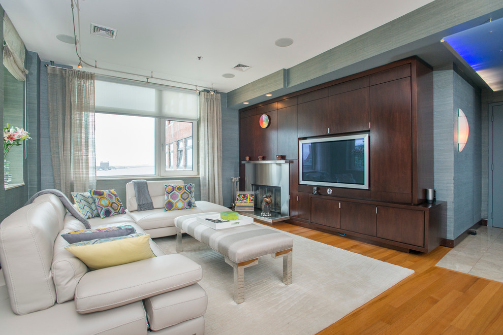 Offenes Modernes Wohnzimmer mit grauer Wandfarbe, braunem Holzboden, Kamin, Kaminumrandung aus Metall und Multimediawand in Boston