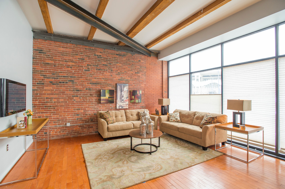 Imagen de salón urbano con paredes grises, suelo de madera en tonos medios y televisor colgado en la pared