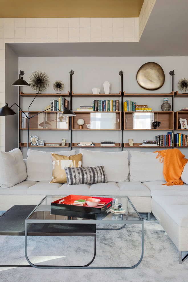 Cette image montre un salon design avec une bibliothèque ou un coin lecture et un mur gris.