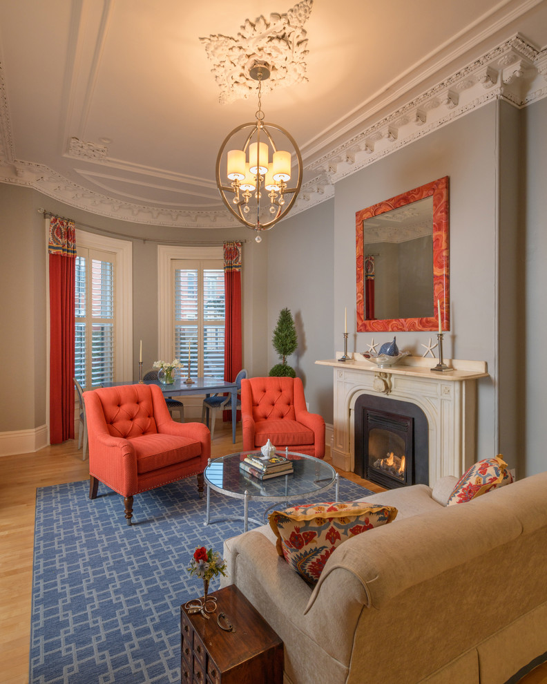 Пример оригинального дизайна: гостиная комната в классическом стиле с серыми стенами, паркетным полом среднего тона, стандартным камином и коричневым полом