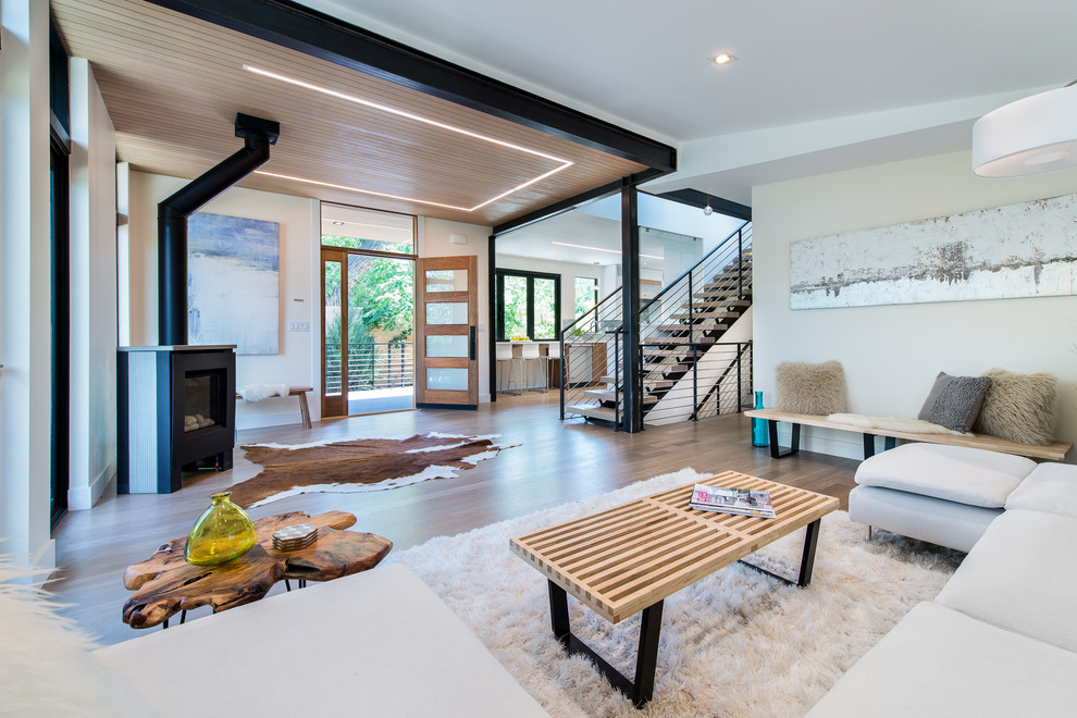 Immagine di un soggiorno minimal di medie dimensioni e aperto con pareti bianche, pavimento in legno massello medio e stufa a legna