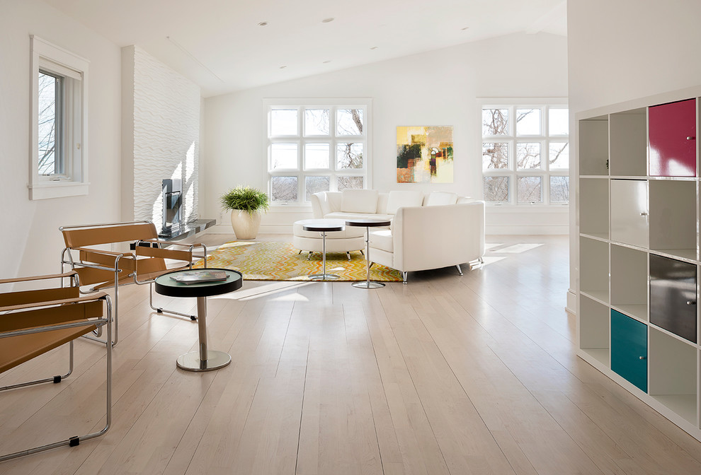 This is an example of a contemporary open plan living room in Denver with white walls and light hardwood flooring.