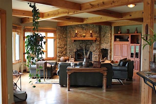 This is an example of a medium sized rustic formal open plan living room in Denver with beige walls, concrete flooring, a standard fireplace, a stone fireplace surround, no tv and beige floors.