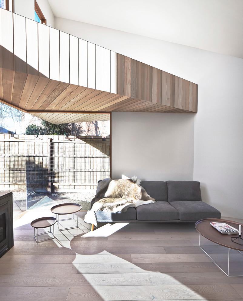 Cette image montre un salon design de taille moyenne et ouvert avec un mur blanc et un sol en bois brun.