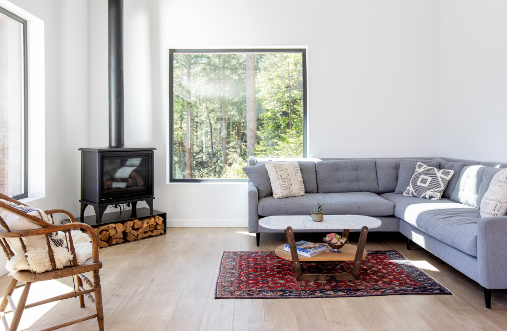 Imagen de salón contemporáneo con paredes blancas, suelo de madera clara, estufa de leña y suelo beige