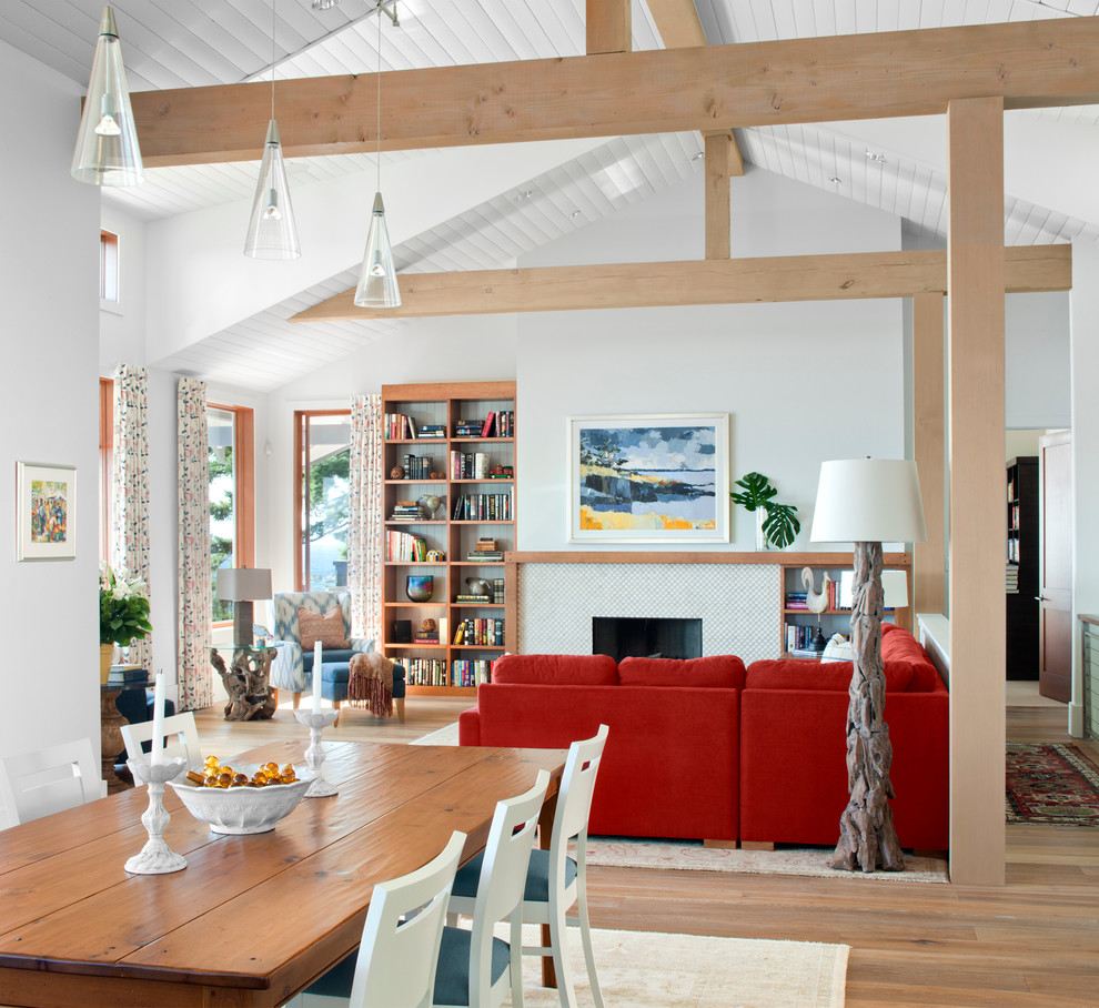 Modelo de salón abierto actual sin televisor con paredes blancas, suelo de madera en tonos medios y marco de chimenea de baldosas y/o azulejos