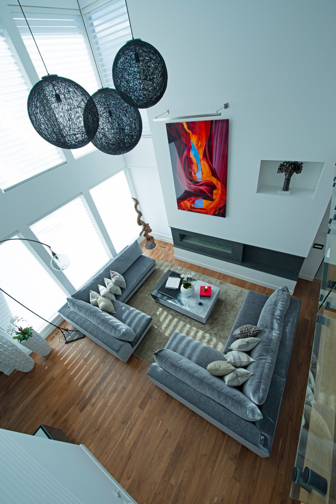 Стильный дизайн: огромная двухуровневая гостиная комната в современном стиле с белыми стенами, паркетным полом среднего тона, горизонтальным камином, фасадом камина из плитки, скрытым телевизором и коричневым полом - последний тренд