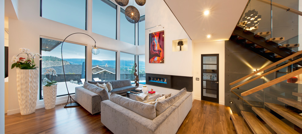 Geräumiges Modernes Wohnzimmer im Loft-Stil mit weißer Wandfarbe, braunem Holzboden, Gaskamin, gefliester Kaminumrandung, verstecktem TV und braunem Boden in Sonstige