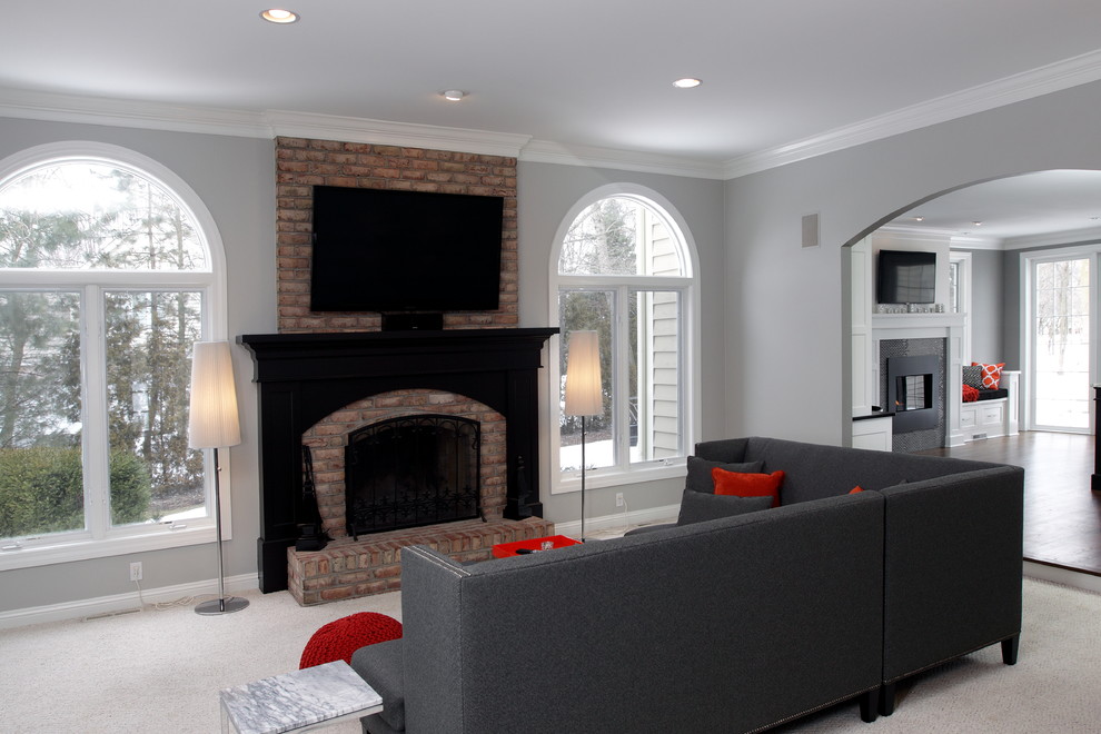 Imagen de salón cerrado clásico de tamaño medio con paredes grises, moqueta, todas las chimeneas, marco de chimenea de ladrillo y televisor colgado en la pared
