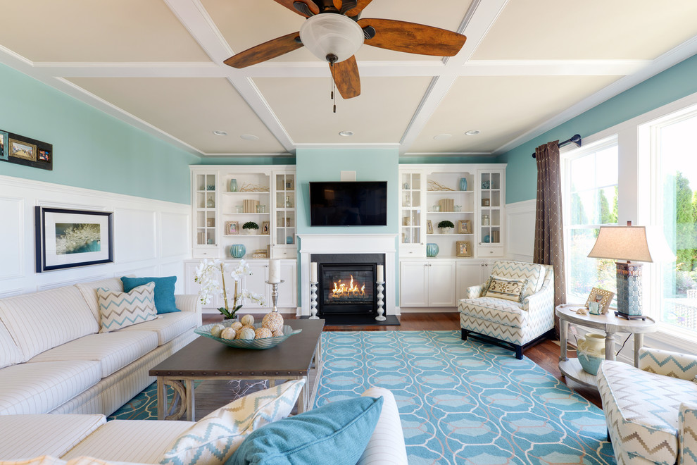 Esempio di un soggiorno costiero con pareti blu, parquet scuro, camino classico e TV a parete