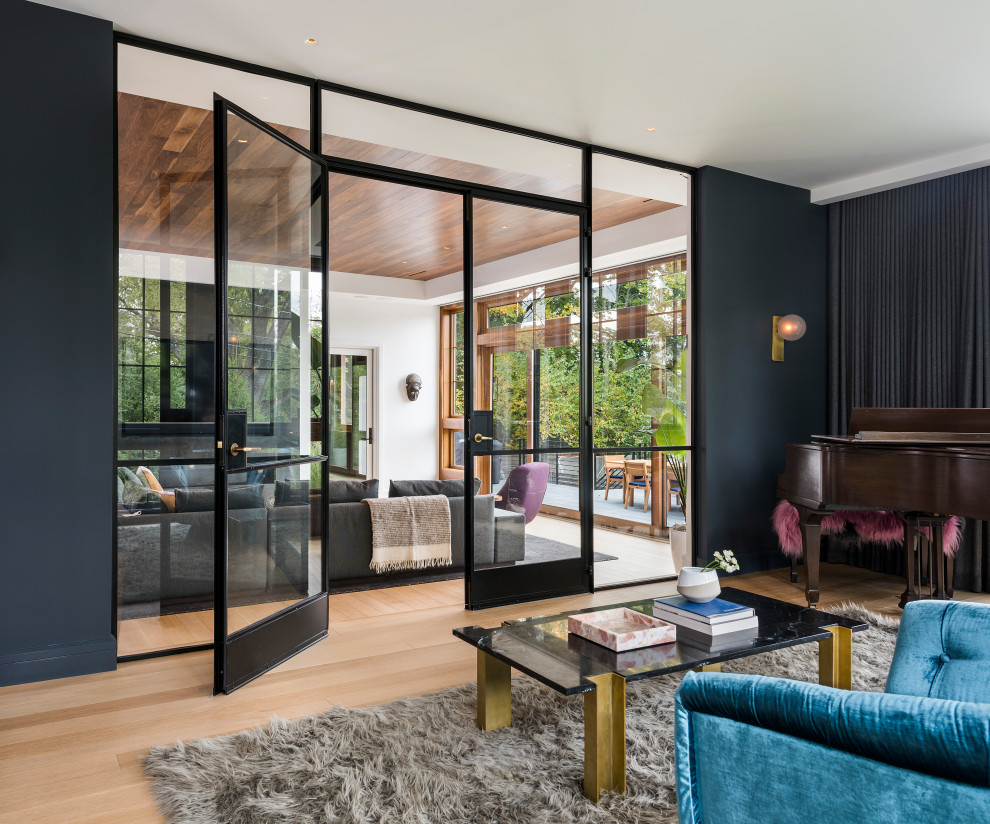 Inspiration för moderna separata vardagsrum, med ljust trägolv, ett musikrum, blå väggar, en bred öppen spis, en spiselkrans i metall och en inbyggd mediavägg