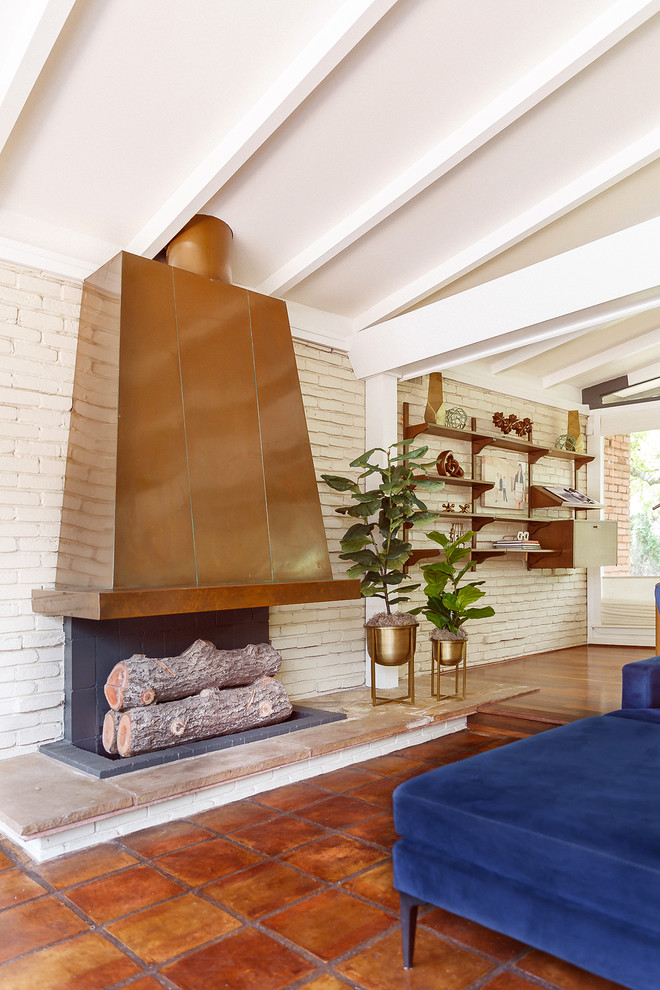 Источник вдохновения для домашнего уюта: большая открытая гостиная комната в стиле ретро с белыми стенами, полом из терракотовой плитки, горизонтальным камином, фасадом камина из камня и коричневым полом