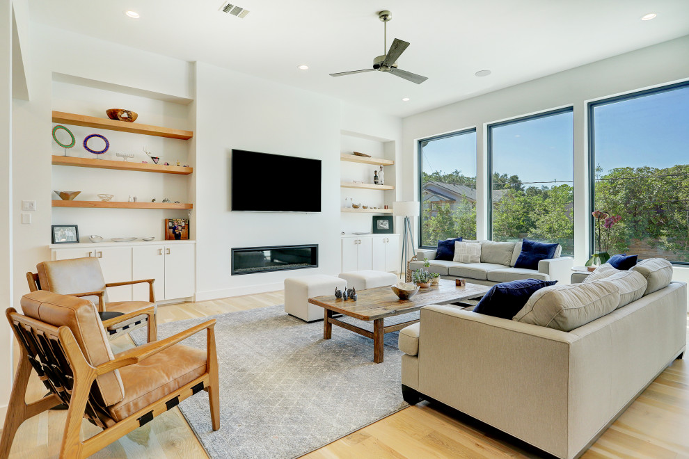 Ejemplo de salón abierto contemporáneo con paredes blancas, suelo de madera clara, chimenea lineal, televisor colgado en la pared y suelo beige