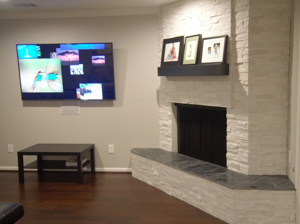 Imagen de salón abierto contemporáneo de tamaño medio con paredes grises, suelo laminado, chimenea de esquina, marco de chimenea de ladrillo, televisor colgado en la pared y suelo marrón