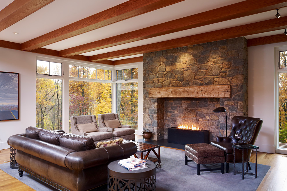 Inspiration pour un grand salon rustique avec un sol en bois brun, un manteau de cheminée en pierre et une cheminée standard.