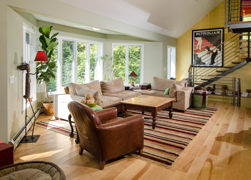 Cette image montre un salon design de taille moyenne et ouvert avec un mur multicolore, un sol en bois brun, une cheminée standard et un manteau de cheminée en pierre.