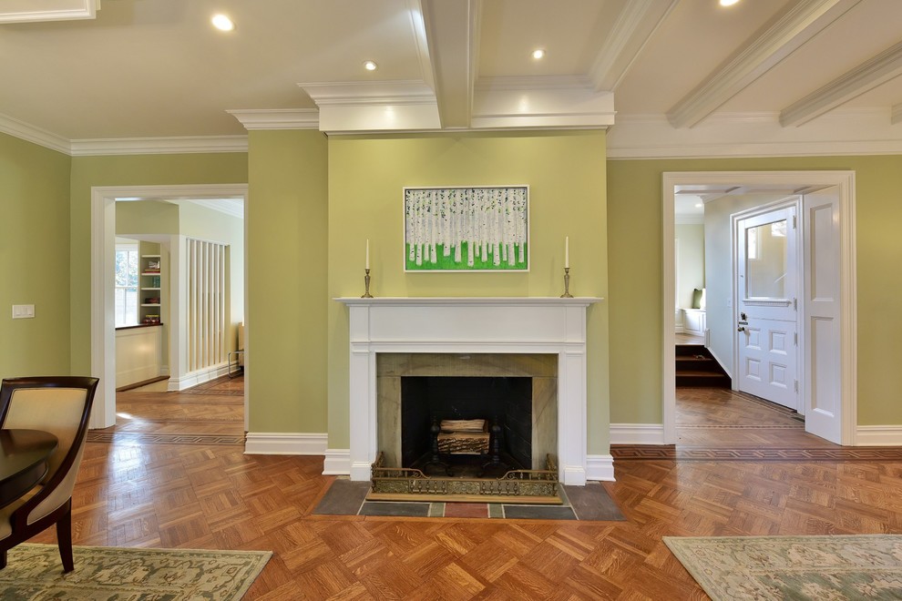 Cette photo montre un grand salon victorien ouvert avec une salle de réception, un mur vert, un sol en bois brun, une cheminée standard et un manteau de cheminée en pierre.