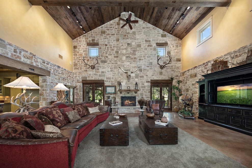 Mountain style open concept brown floor living room photo in Austin with yellow walls, a standard fireplace, a stone fireplace and a tv stand