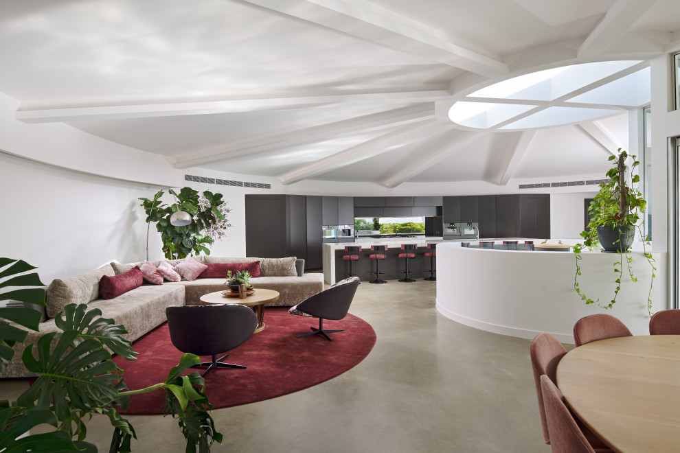 Immagine di un ampio soggiorno contemporaneo aperto con pareti bianche, pavimento in cemento, pavimento grigio e travi a vista
