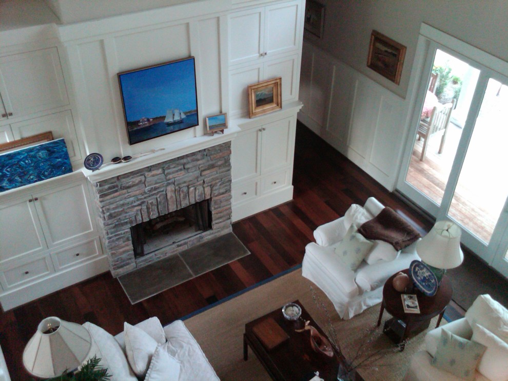 На фото: двухуровневая гостиная комната среднего размера в стиле неоклассика (современная классика) с белыми стенами, темным паркетным полом, стандартным камином и фасадом камина из камня с