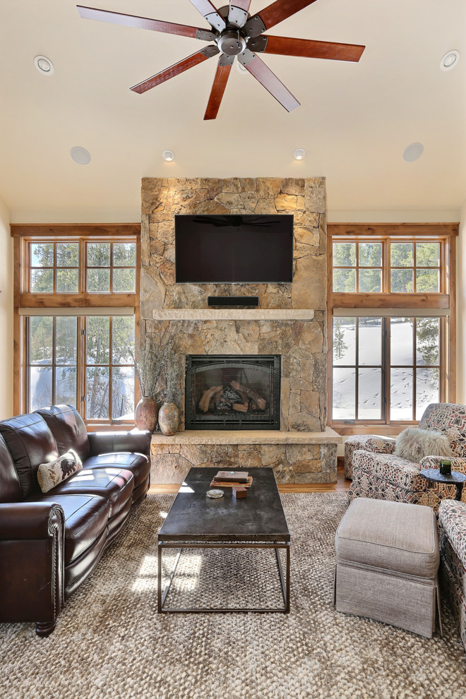 Rustikales Wohnzimmer mit beiger Wandfarbe, braunem Holzboden, Kamin und Kaminumrandung aus Stein in Denver