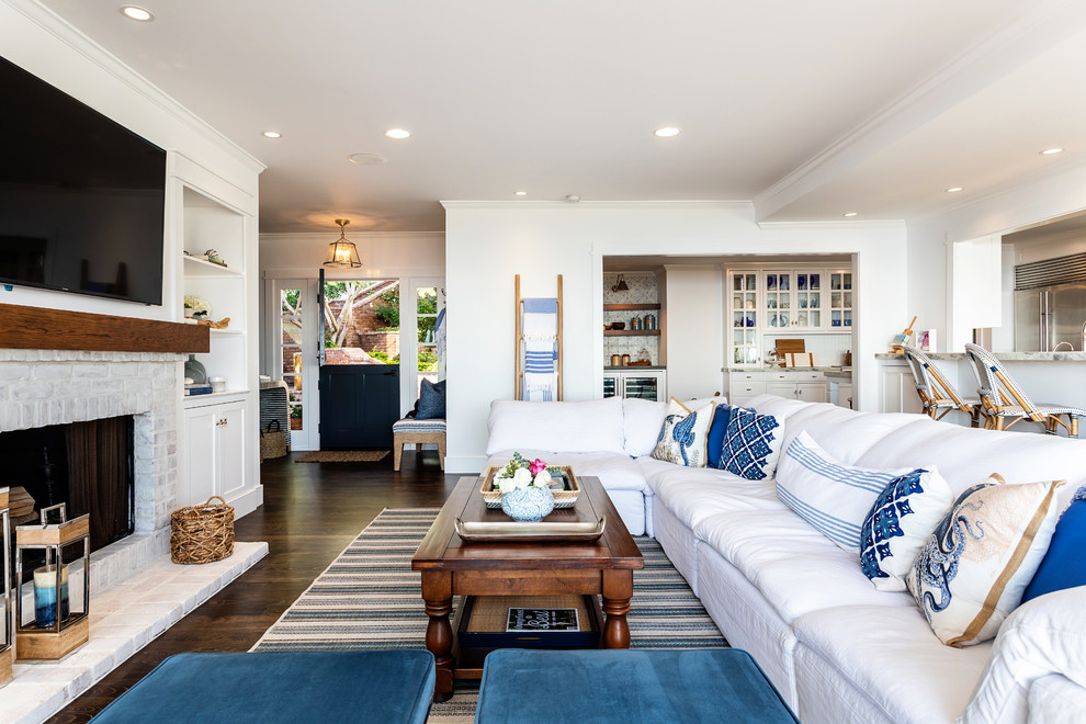 This is an example of a large beach style formal open plan living room in Sacramento with white walls, dark hardwood flooring, a standard fireplace, a concrete fireplace surround, a wall mounted tv and brown floors.