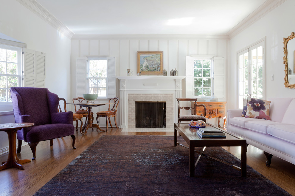 Bild på ett stort vintage separat vardagsrum, med ett finrum, vita väggar, mellanmörkt trägolv, en standard öppen spis, en spiselkrans i tegelsten och brunt golv