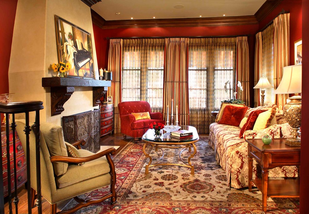 На фото: парадная, изолированная гостиная комната в средиземноморском стиле с красными стенами, паркетным полом среднего тона, стандартным камином и фасадом камина из штукатурки с