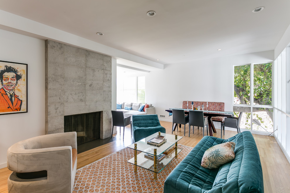 Пример оригинального дизайна: гостиная комната в современном стиле с светлым паркетным полом, стандартным камином и фасадом камина из бетона без телевизора