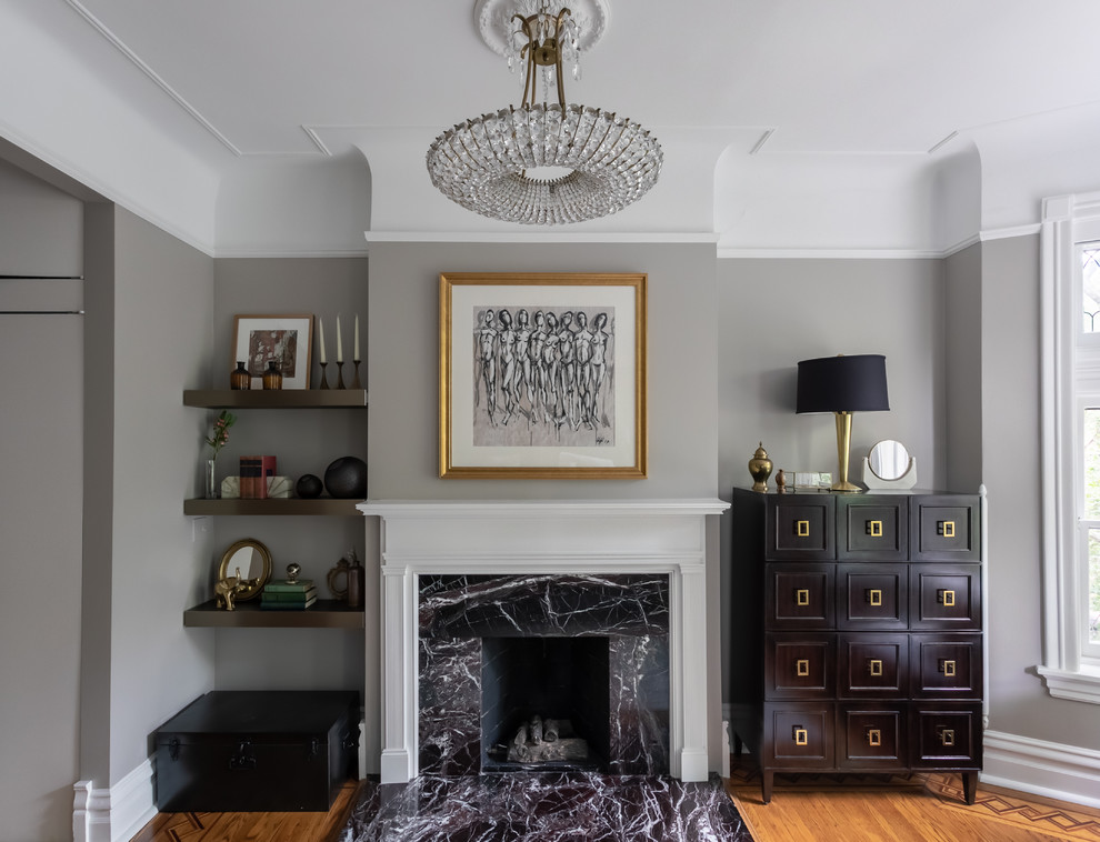 Klassisches Wohnzimmer mit grauer Wandfarbe, braunem Holzboden, Kamin, Kaminumrandung aus Stein und braunem Boden in Chicago