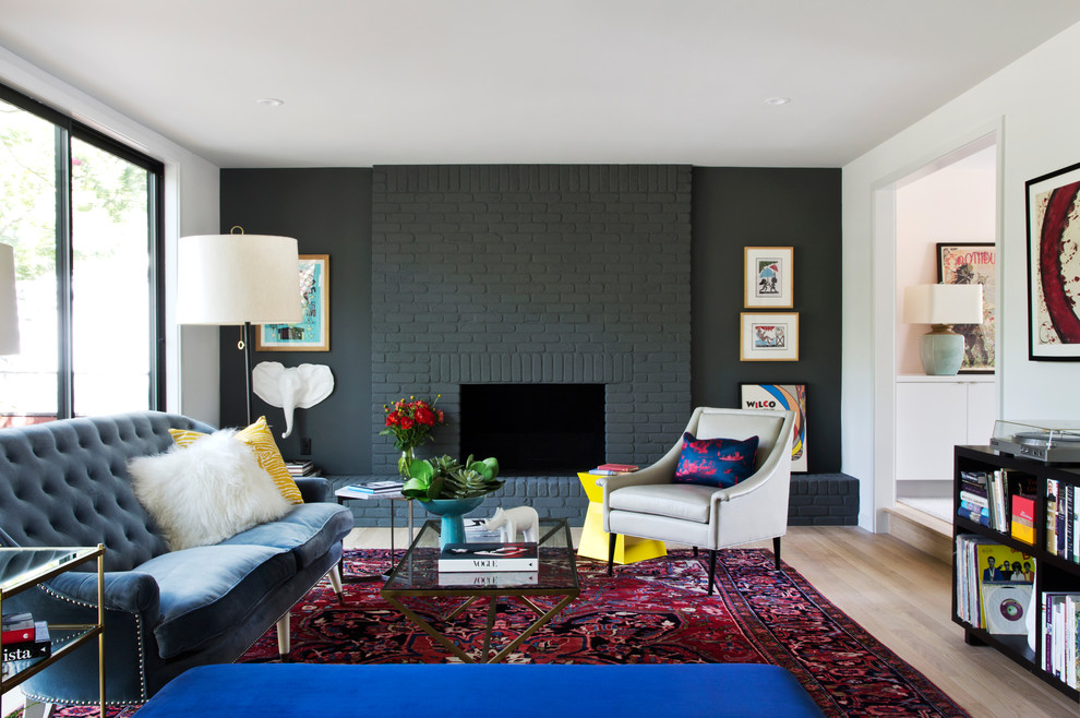 Cette image montre un salon design avec un mur noir, une cheminée standard, un manteau de cheminée en brique et parquet clair.