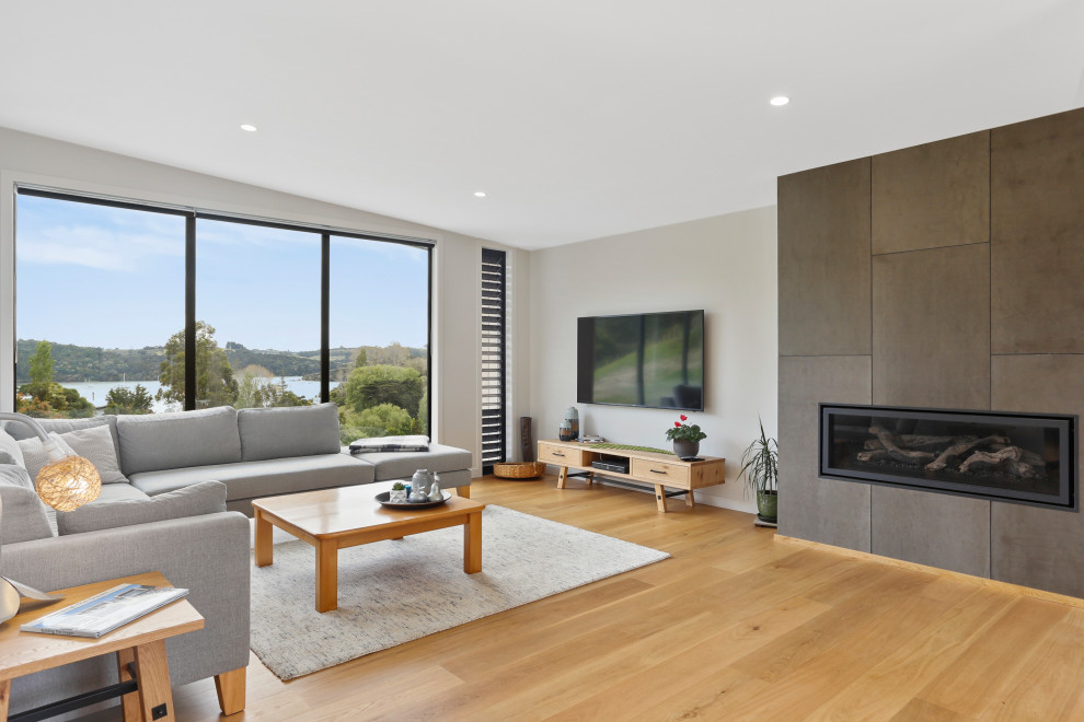 Contemporary open plan living room in Auckland with grey walls, medium hardwood flooring, a ribbon fireplace, a wall mounted tv and brown floors.