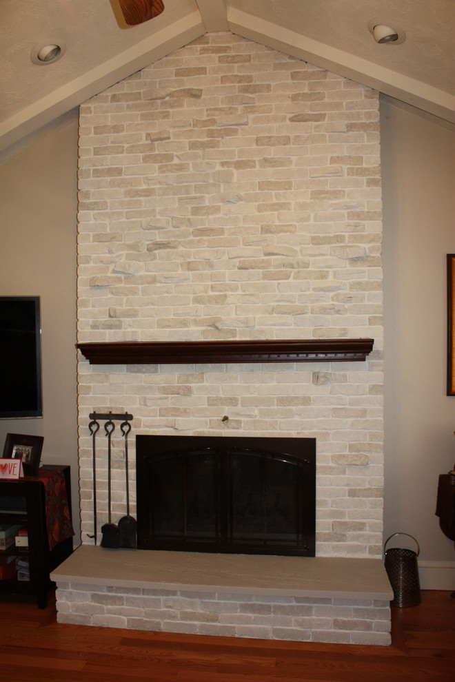 Пример оригинального дизайна: гостиная комната в классическом стиле с фасадом камина из кирпича