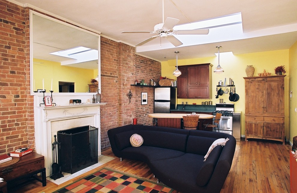 Exemple d'un salon mansardé ou avec mezzanine éclectique de taille moyenne avec un mur jaune, un sol en bois brun, une cheminée standard, un manteau de cheminée en bois et un téléviseur indépendant.