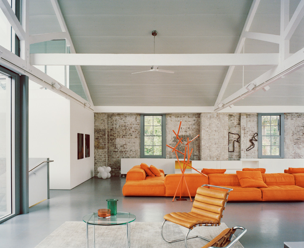 Imagen de salón abierto y abovedado urbano con paredes blancas, suelo de cemento, suelo gris y ladrillo