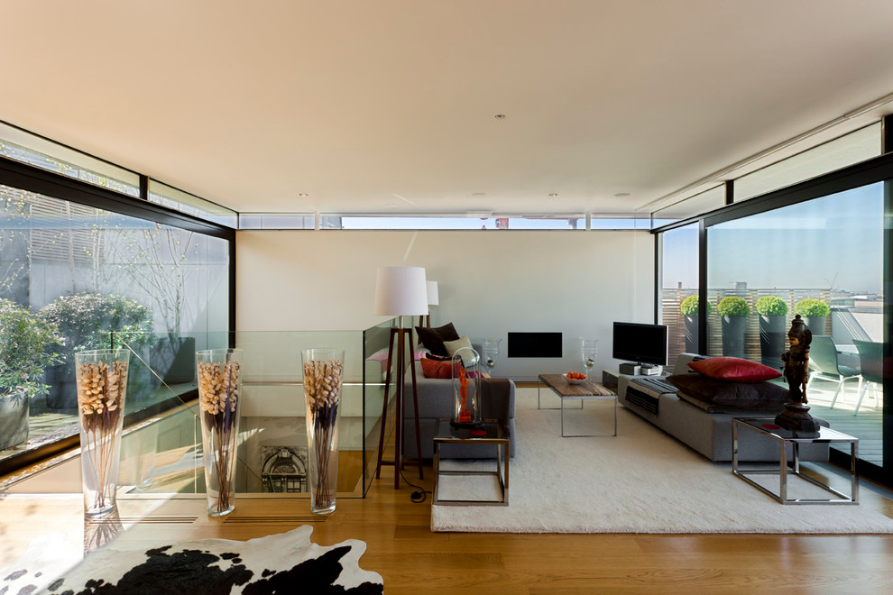 Inredning av ett modernt vardagsrum, med ett finrum, vita väggar, ljust trägolv, en fristående TV och en bred öppen spis