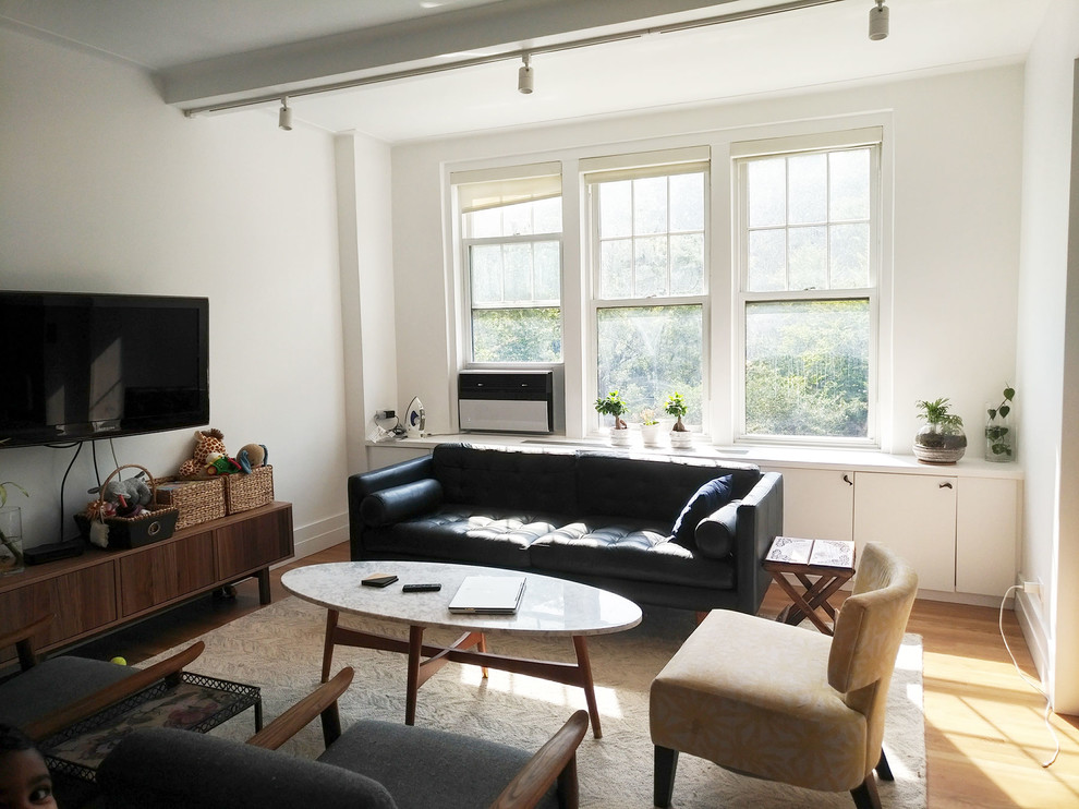 Diseño de salón abierto retro de tamaño medio sin chimenea con paredes blancas, suelo de madera clara y televisor colgado en la pared