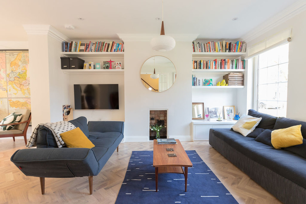 ロンドンにある高級な中くらいなコンテンポラリースタイルのおしゃれなLDK (淡色無垢フローリング、標準型暖炉、ライブラリー、グレーの壁、壁掛け型テレビ、茶色い床、青いソファ) の写真