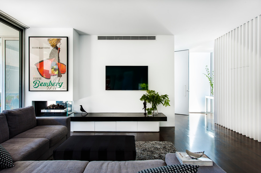 Imagen de salón abierto minimalista pequeño con paredes blancas, suelo de madera oscura y chimenea de doble cara