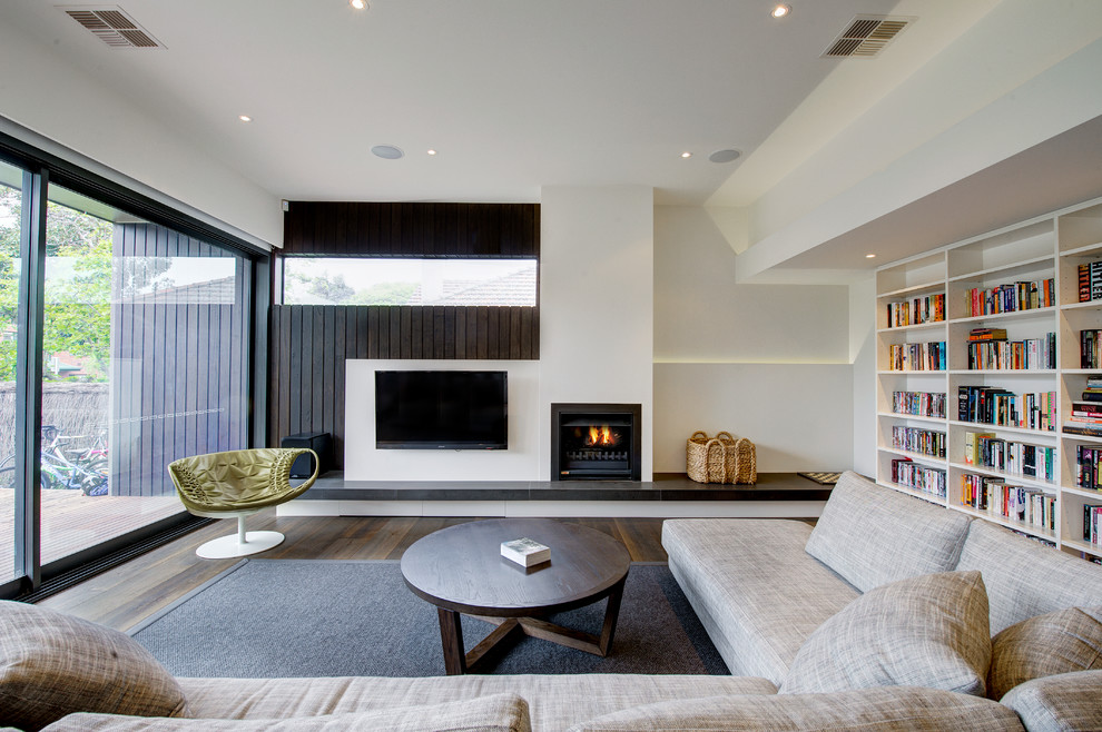 Moderne Bibliothek mit weißer Wandfarbe, braunem Holzboden, Kamin und TV-Wand in Melbourne